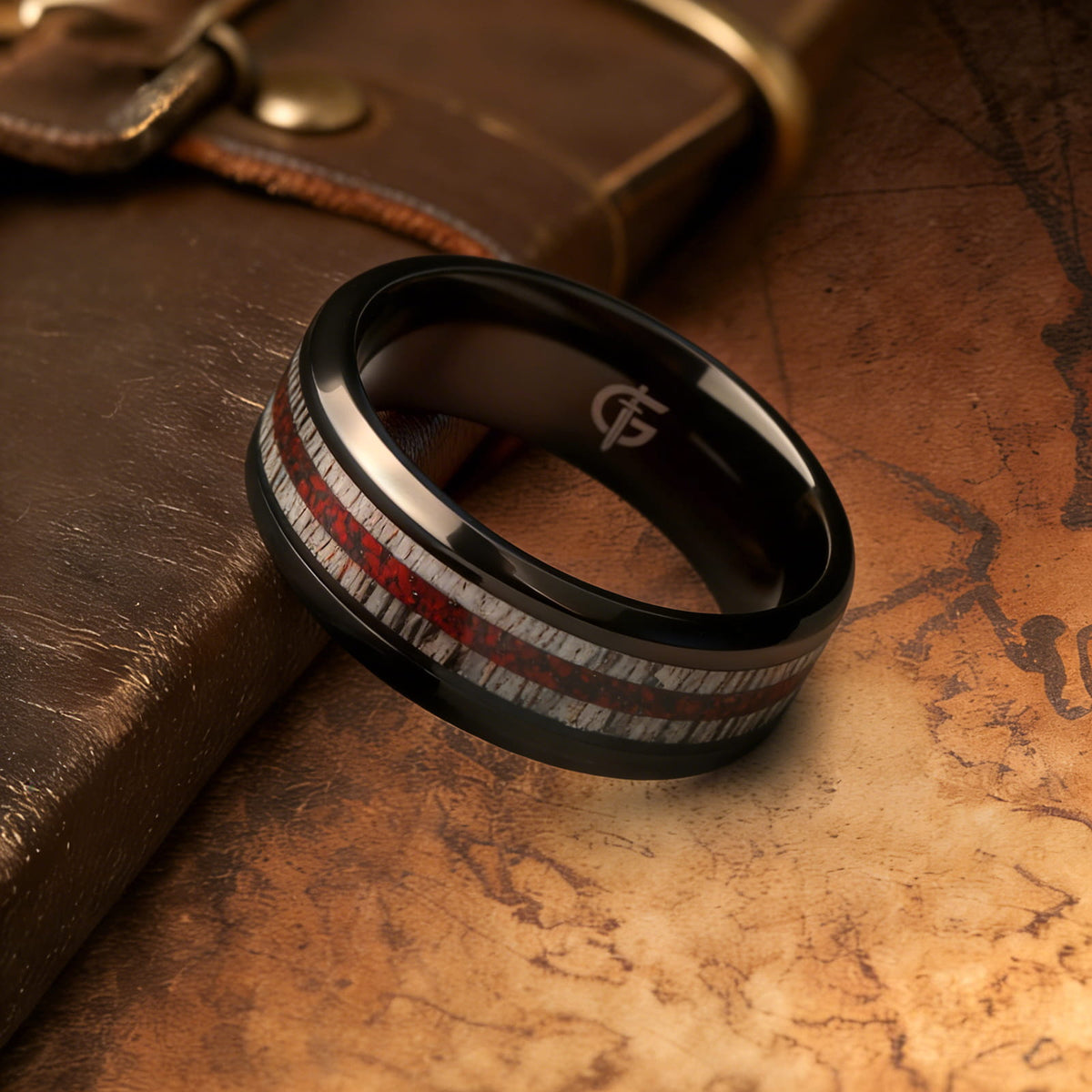 Black titanium ring with pale deer antler bands flanking a reddish mixed inlay and beveled edges