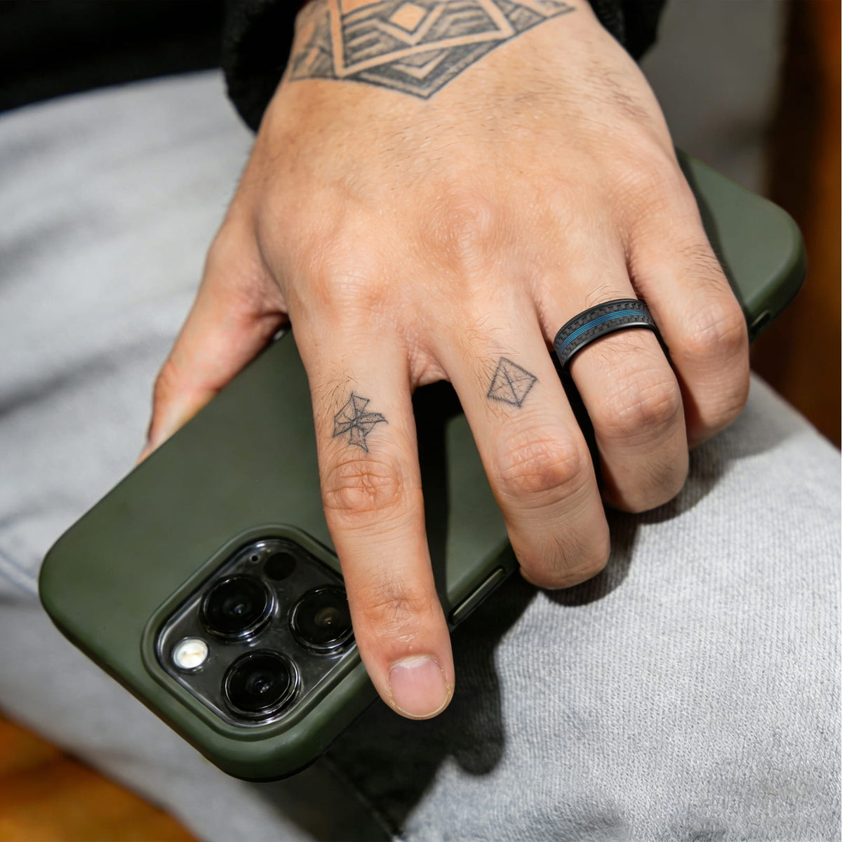 Polished black tungsten carbide ring with blue fishing line centered between two black carbon fiber strips.