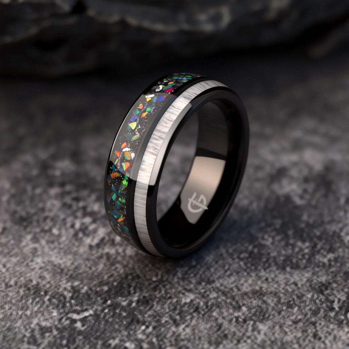 Polished black tungsten ring with pale deer antler beside multicolored opal and silver-colored meteorite fragments