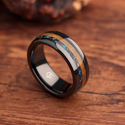 Polished black ceramic ring with brown wood beside blue-green, red and silver-gray inlay fragments.