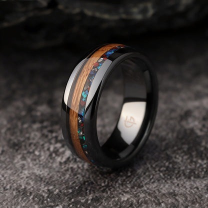 Polished black ceramic ring with brown wood beside blue-green, red and silver-gray inlay fragments.