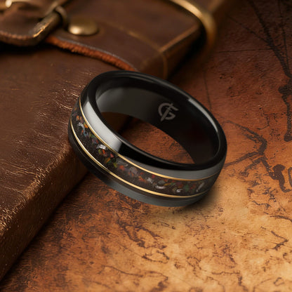 Polished black ceramic ring with multicolored natural opal and silver-gray meteorite fragments framed by two thin brass lines.