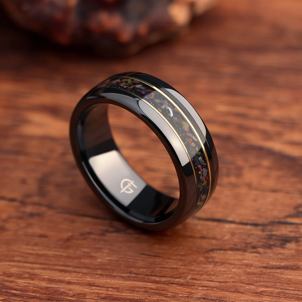 Polished black ceramic ring with multicolored natural opal and silver-gray meteorite fragments framed by two thin brass lines.