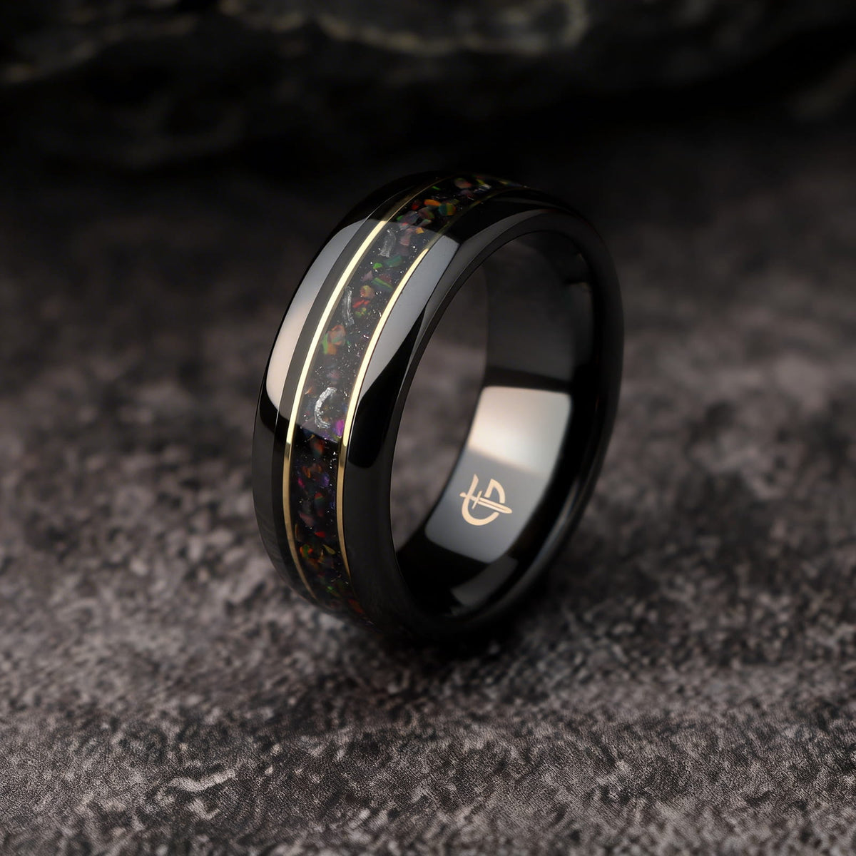 Polished black ceramic ring with multicolored natural opal and silver-gray meteorite fragments framed by two thin brass lines.