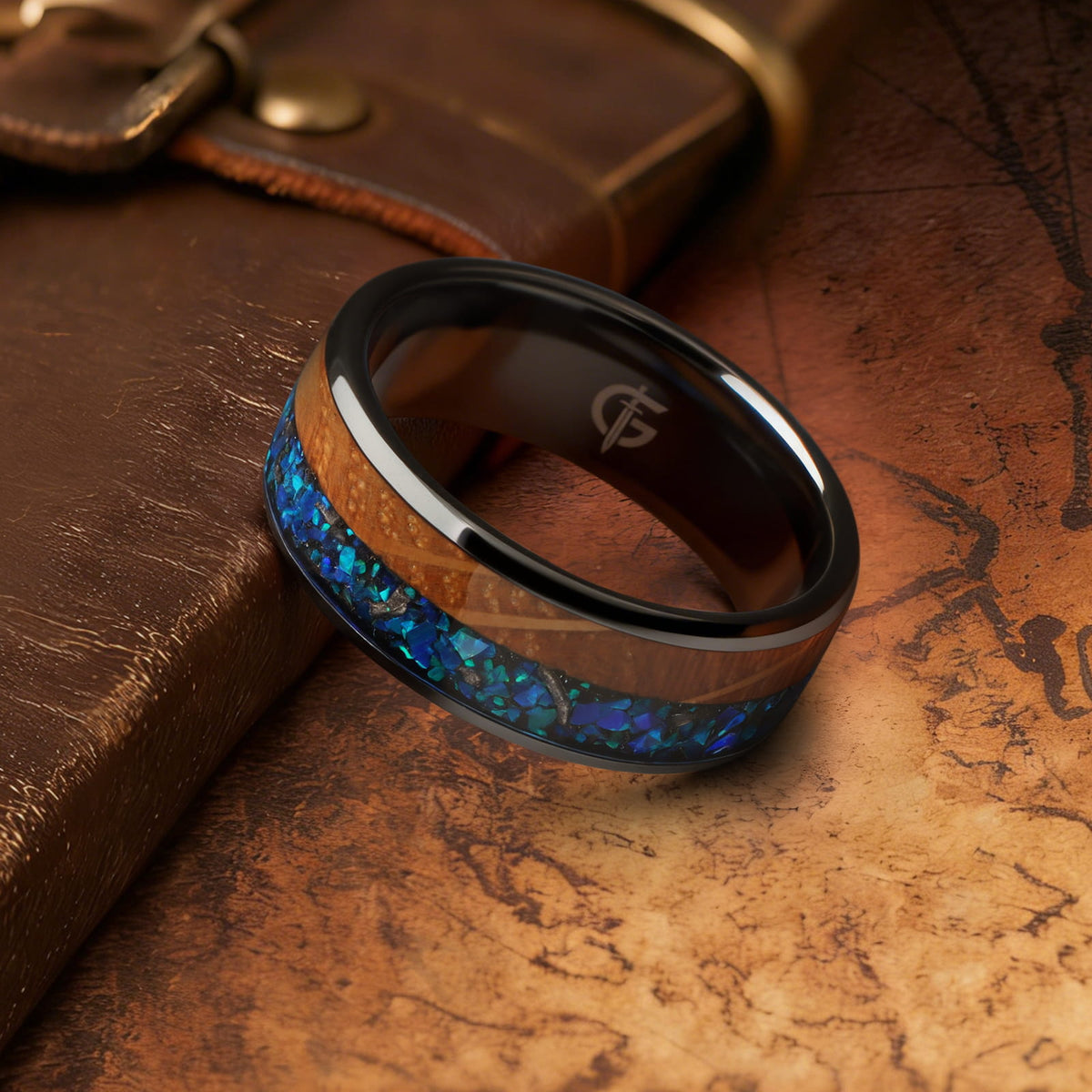 Flat black ceramic ring with brown whiskey barrel wood beside blue natural opal and silver-gray meteorite