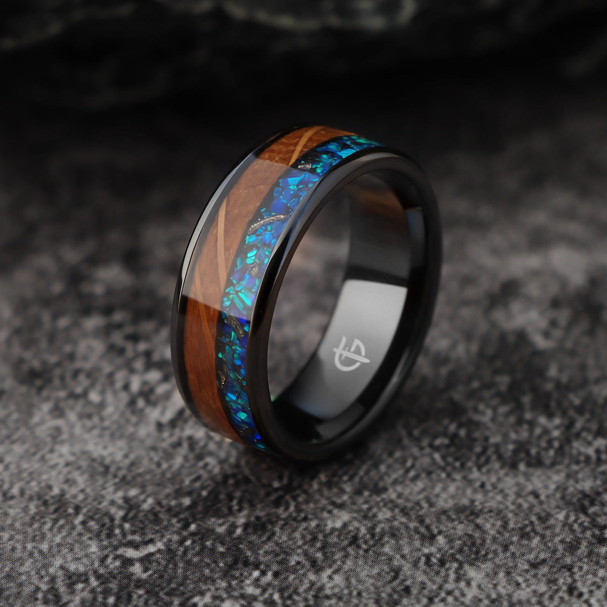 Flat black ceramic ring with brown whiskey barrel wood beside blue natural opal and silver-gray meteorite