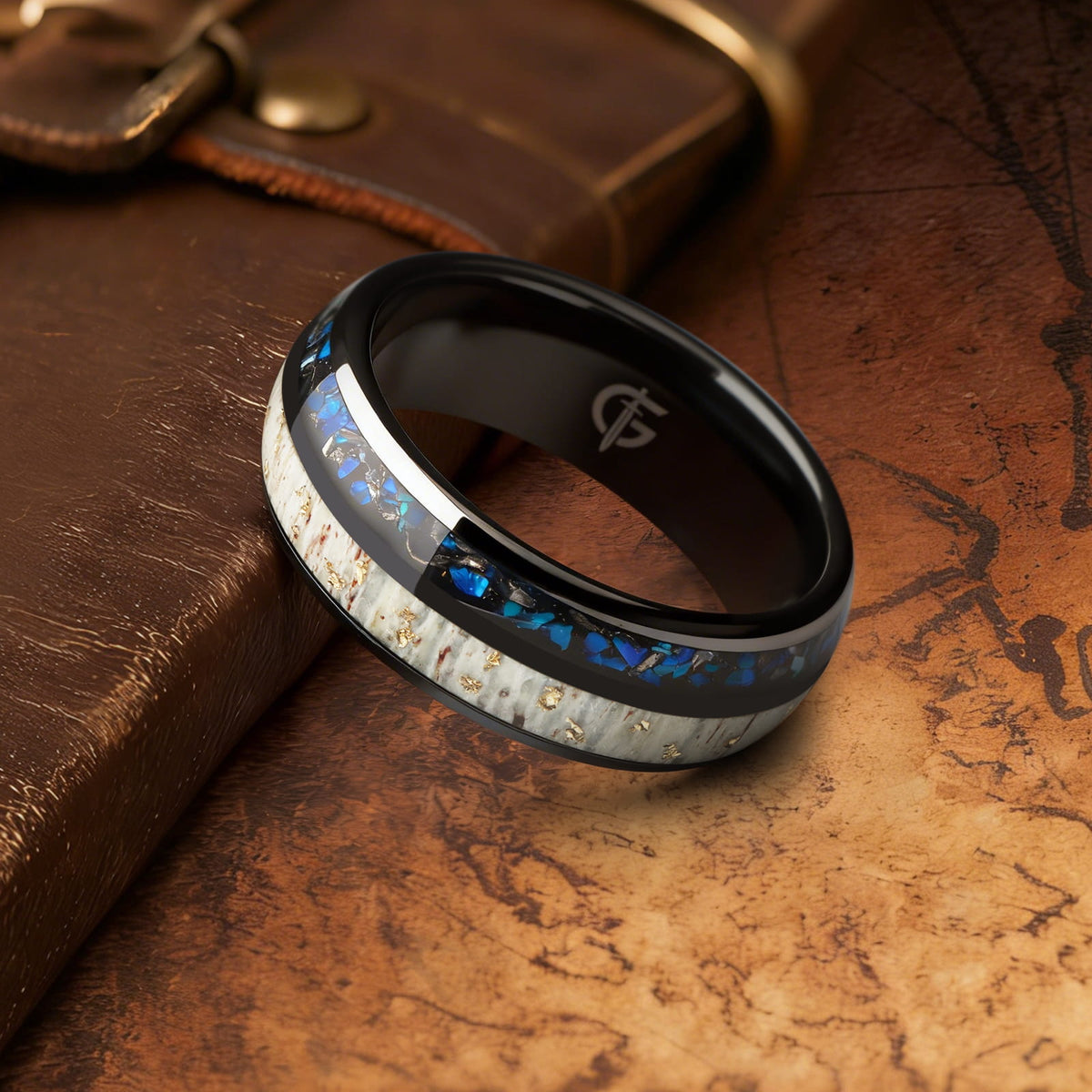Black ceramic ring with gold-flecked antler beside Sleepy Blue natural opal and meteorite fragments