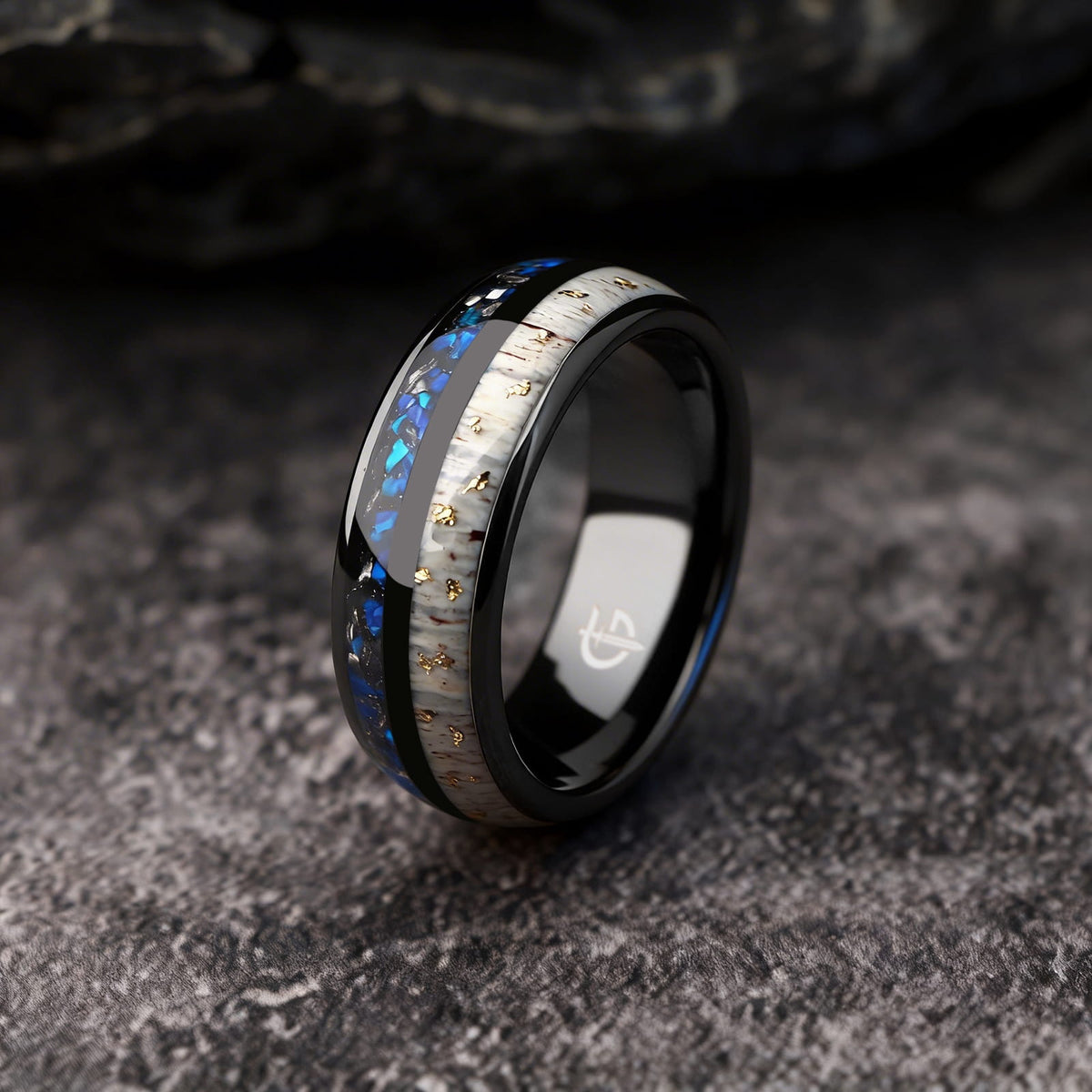 Black ceramic ring with gold-flecked antler beside Sleepy Blue natural opal and meteorite fragments