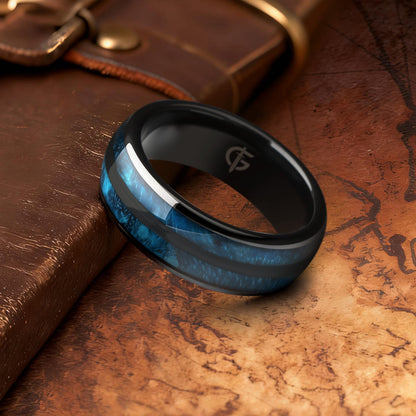 Polished black ceramic ring with two blue whiskey barrel wood inlays separated by a black center strip.