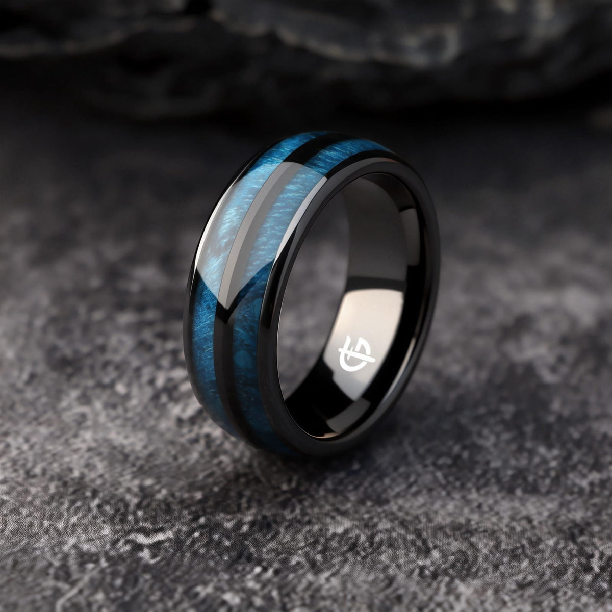 Polished black ceramic ring with two blue whiskey barrel wood inlays separated by a black center strip.