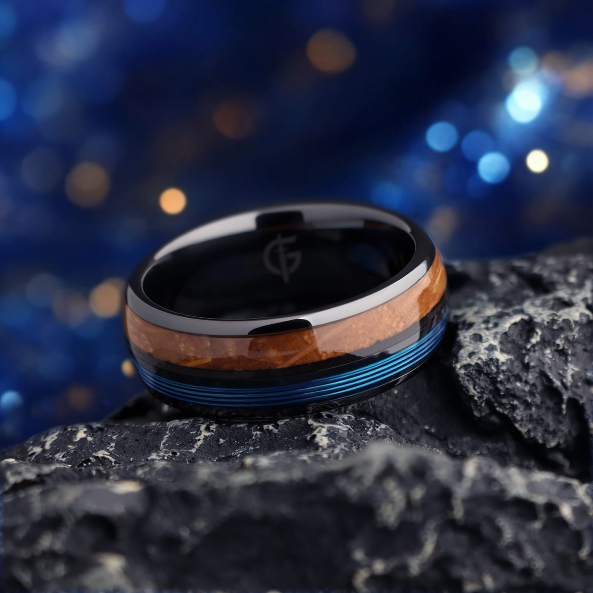 Black ceramic ring with brown whiskey barrel wood and blue fishing line inlays separated by a black strip.