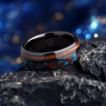 Black ceramic ring with reddish dinosaur bone and blue natural opal beside brown whiskey barrel wood