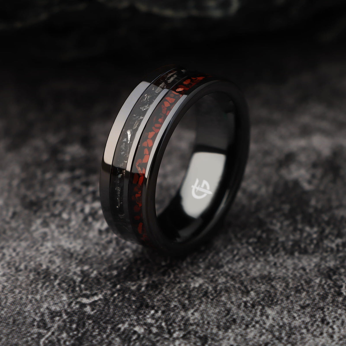Flat black ceramic ring with red agate and dinosaur bone beside silver-gray meteorite and black agate