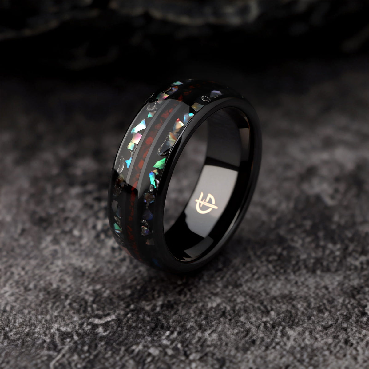 Black ceramic ring with red dinosaur bone center between two iridescent abalone shell and silver-gray meteorite bands.