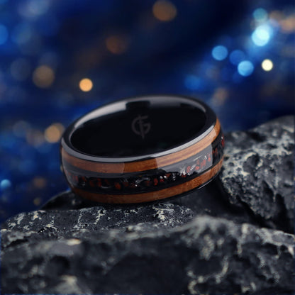 Black ceramic ring with brown wood strips framing silver-gray meteorite and reddish dinosaur bone fragments