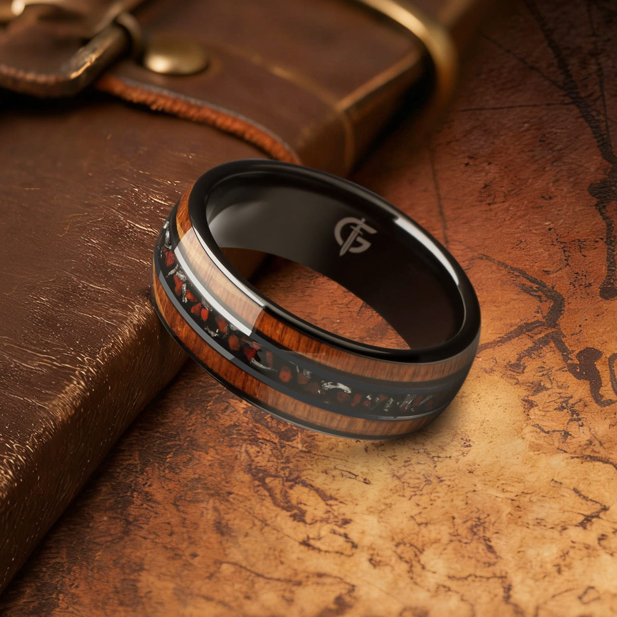 Black ceramic ring with brown wood strips framing silver-gray meteorite and reddish dinosaur bone fragments