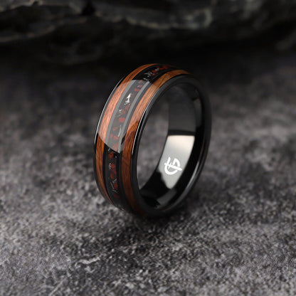Black ceramic ring with brown wood strips framing silver-gray meteorite and reddish dinosaur bone fragments