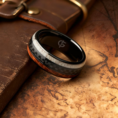 Black ceramic ring with a carbon fiber center between brown wood grain and pale deer antler