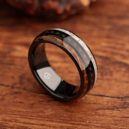 Black ceramic ring with a carbon fiber center between brown wood grain and pale deer antler