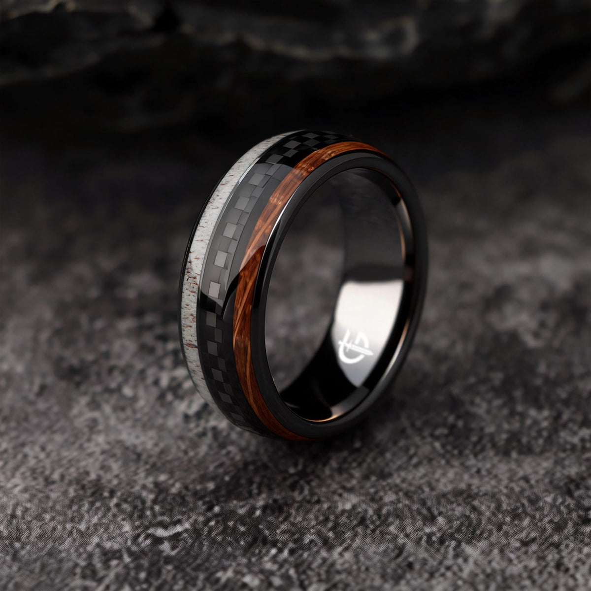 Black ceramic ring with a carbon fiber center between brown wood grain and pale deer antler