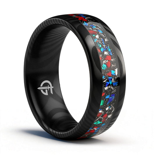 Black patterned Damascus steel ring with a central inlay of red, blue and silver-colored fragments.