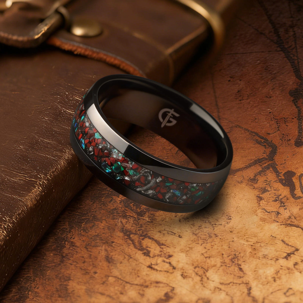 Polished black titanium ring with a mixed inlay of red, blue-green and silver-gray fragments.