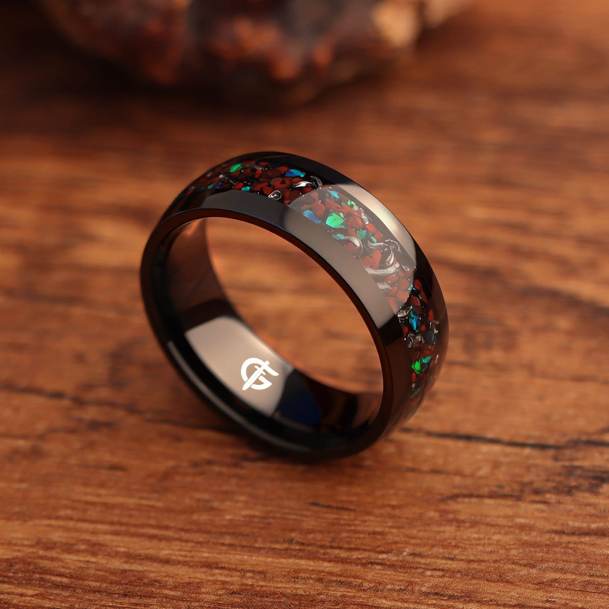Polished black titanium ring with a mixed inlay of red, blue-green and silver-gray fragments.