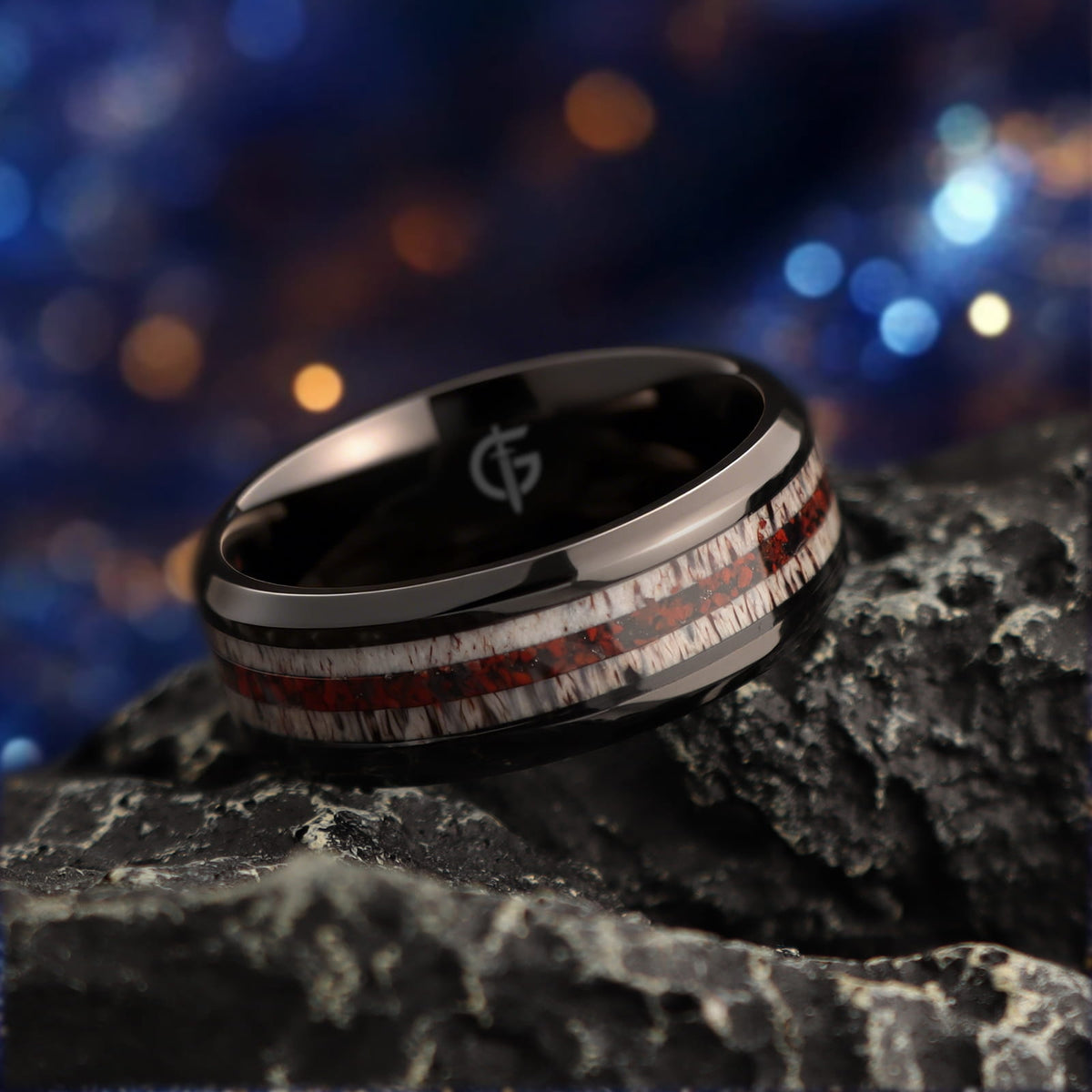 Black titanium ring with pale deer antler bands flanking a reddish mixed inlay and beveled edges