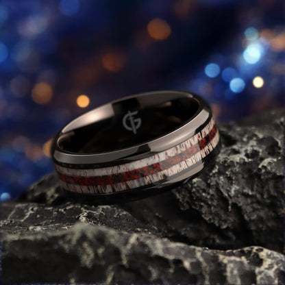 Black titanium ring with pale deer antler bands flanking a reddish mixed inlay and beveled edges