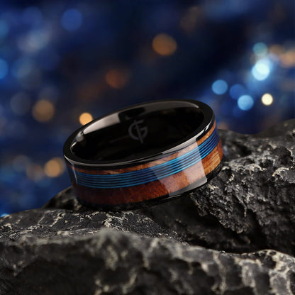 Black titanium ring with blue fishing line centered between brown whiskey barrel wood bands