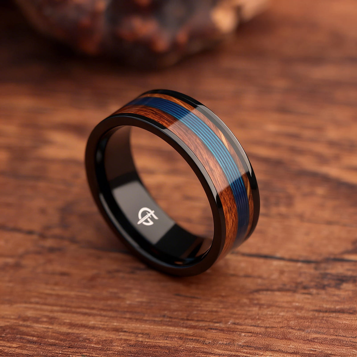 Black titanium ring with blue fishing line centered between brown whiskey barrel wood bands