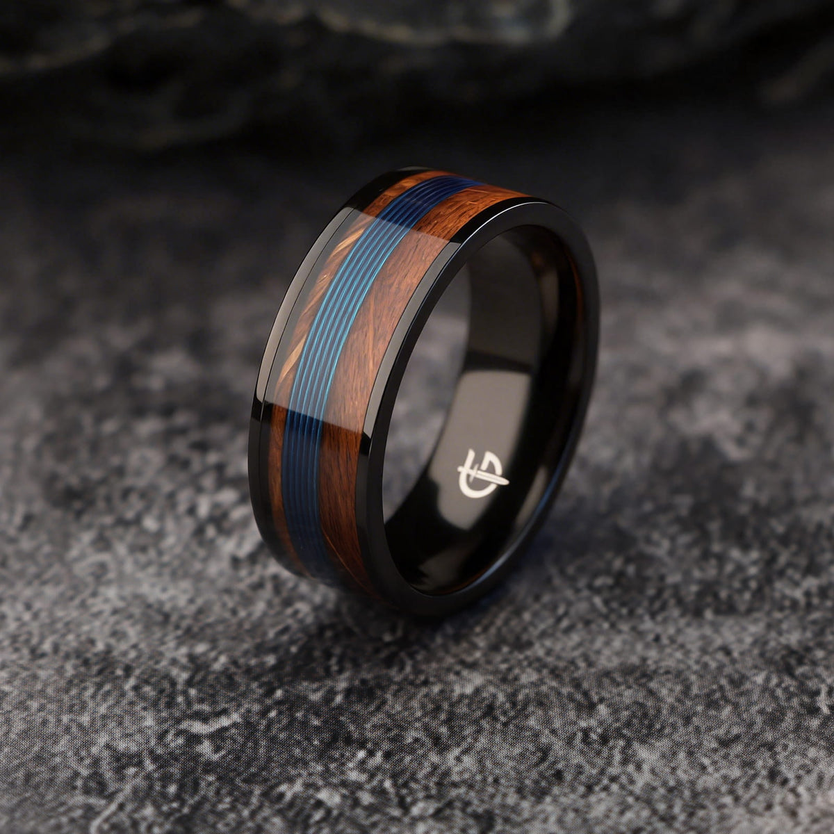 Black titanium ring with blue fishing line centered between brown whiskey barrel wood bands