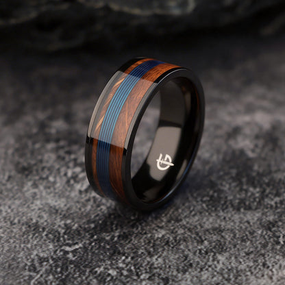 Black titanium ring with blue fishing line centered between brown whiskey barrel wood bands