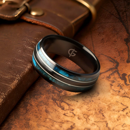 Black titanium ring with blue whiskey barrel wood and silver-tone guitar strings in two mirrored channels