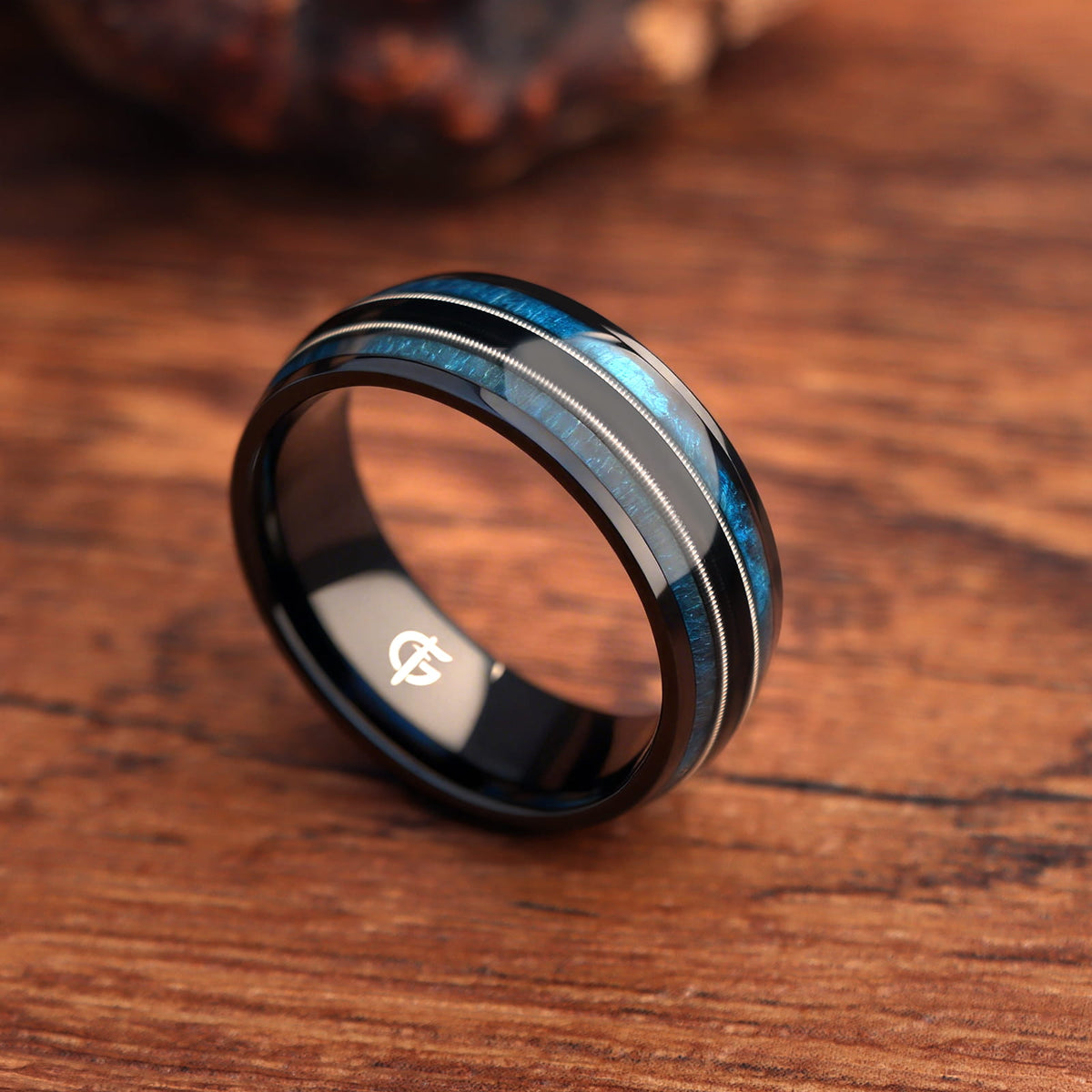 Black titanium ring with blue whiskey barrel wood and silver-tone guitar strings in two mirrored channels