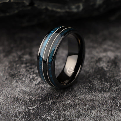 Black titanium ring with blue whiskey barrel wood and silver-tone guitar strings in two mirrored channels