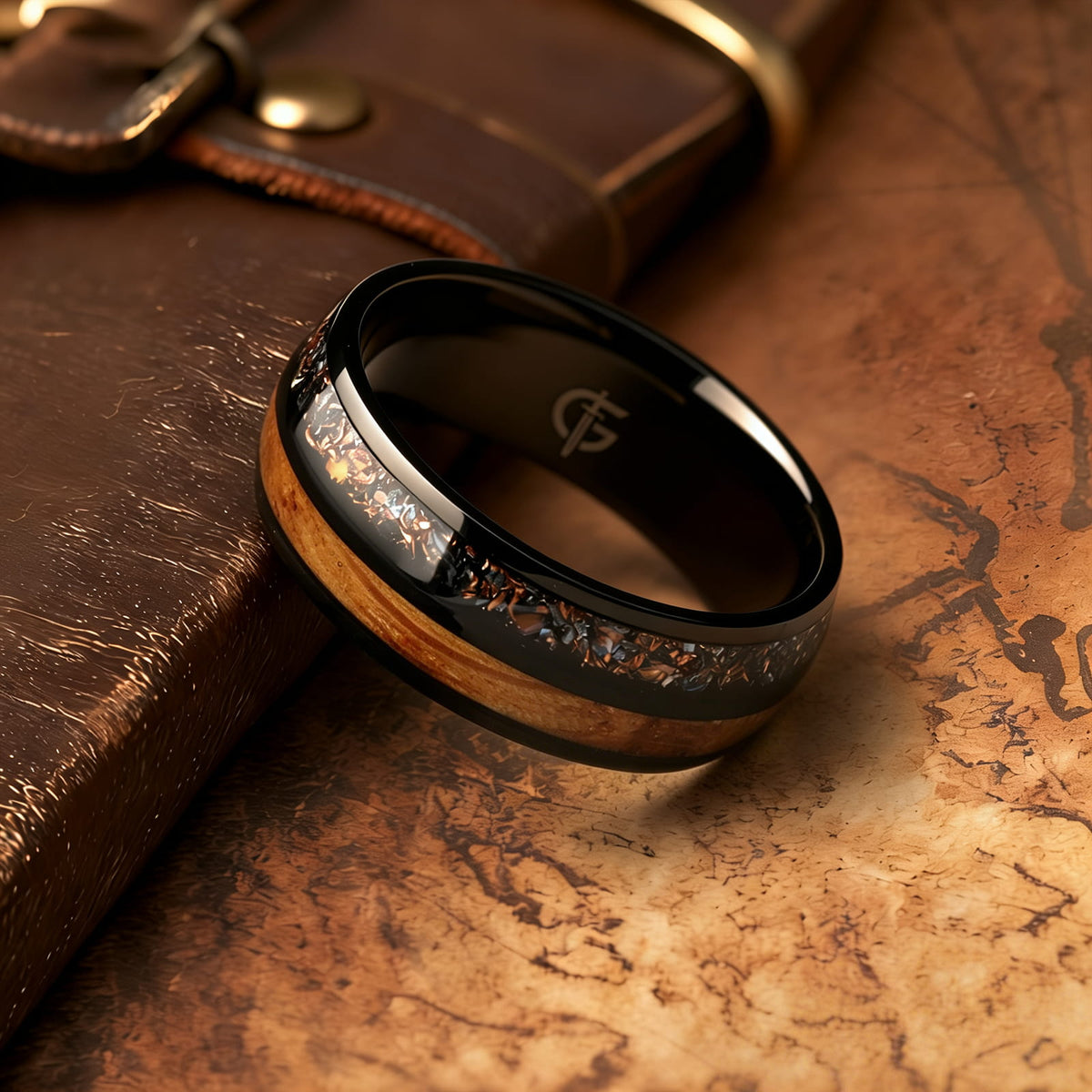 Black titanium ring with whiskey barrel wood beside a silver-gray meteorite, moonstone and copper inlay.