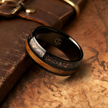 Black titanium ring with whiskey barrel wood beside a silver-gray meteorite, moonstone and copper inlay.