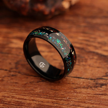 Black titanium ring with two inlays: blue-green opal and meteorite beside reddish-brown bone and copper.