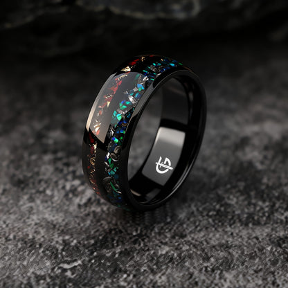 Black titanium ring with two inlays: blue-green opal and meteorite beside reddish-brown bone and copper.