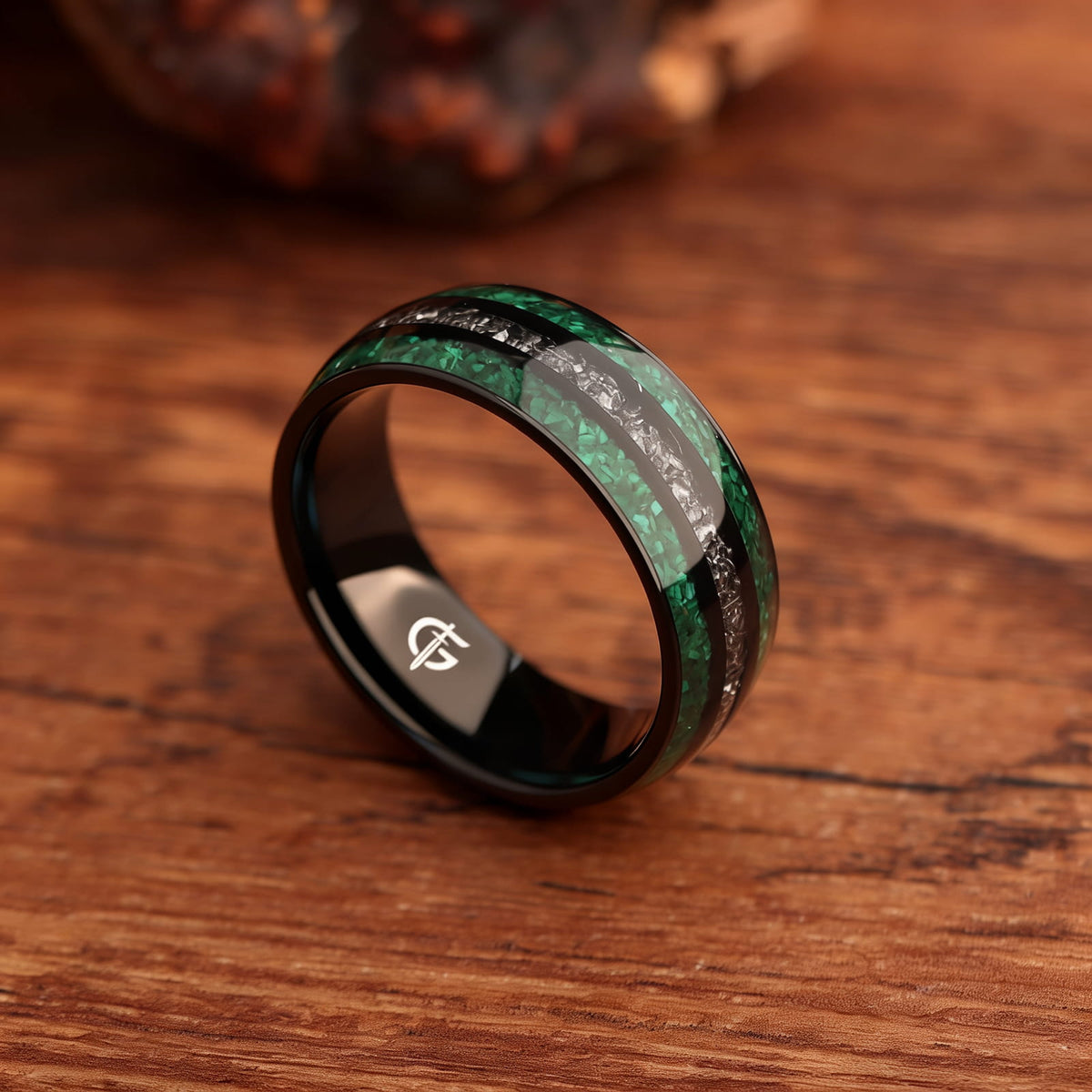 Polished black titanium ring with green malachite channels on either side of silver-gray meteorite.