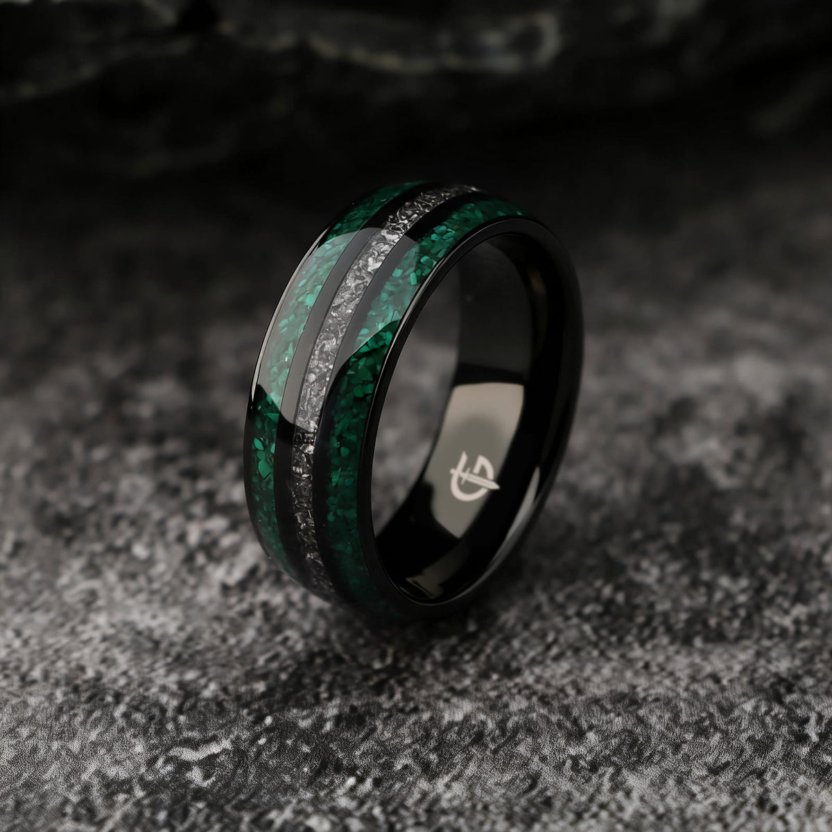 Polished black titanium ring with green malachite channels on either side of silver-gray meteorite.