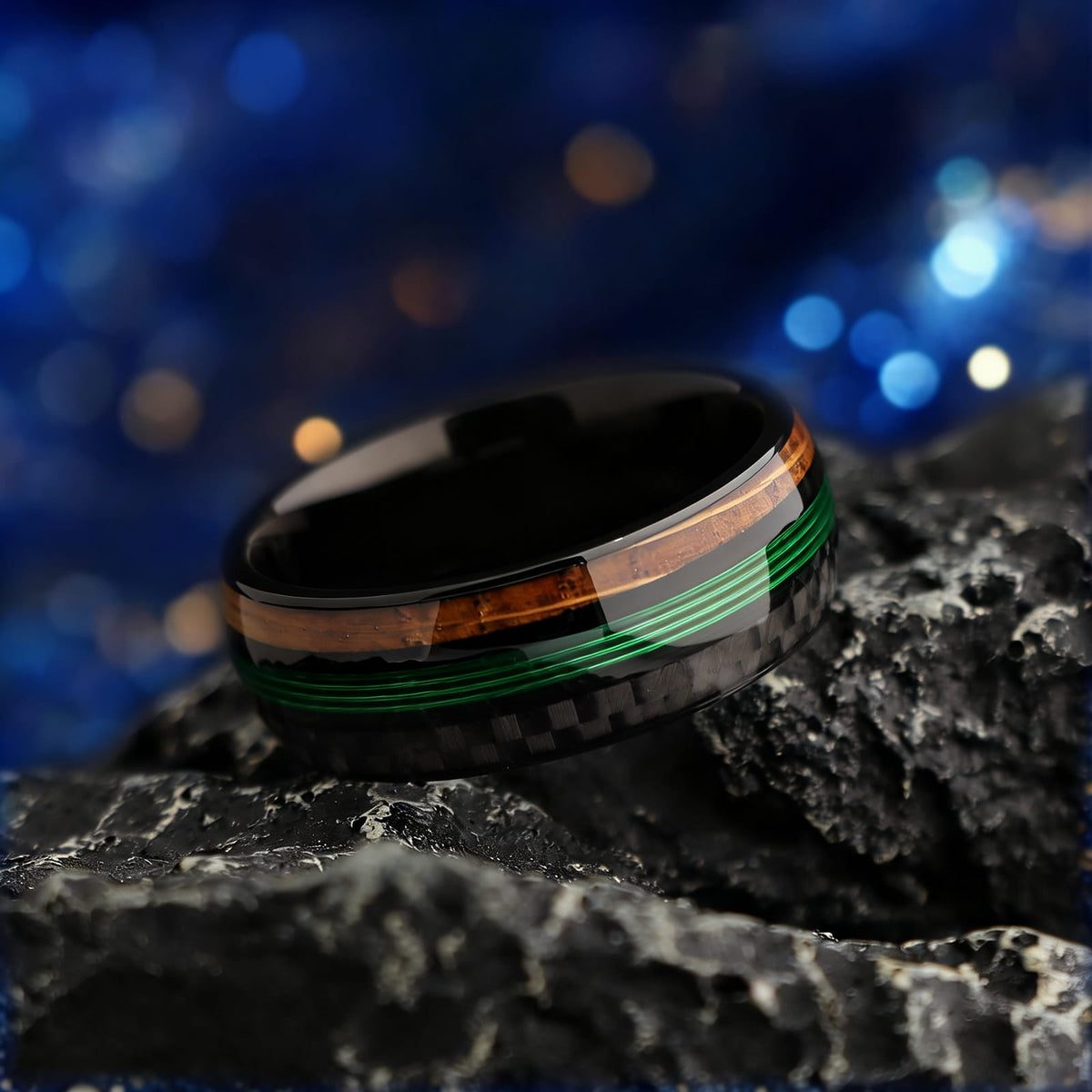 Black titanium ring with green fishing line between brown whiskey barrel wood and black carbon fiber