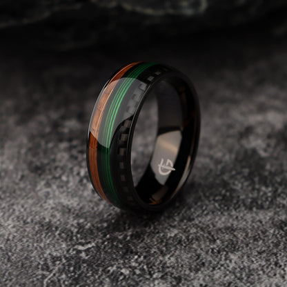 Black titanium ring with green fishing line between brown whiskey barrel wood and black carbon fiber