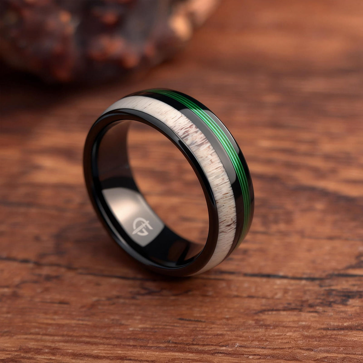 Polished black tungsten ring with pale deer antler beside parallel green fishing line strands