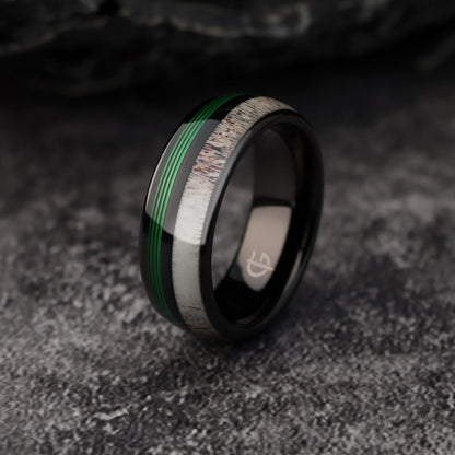 Polished black tungsten ring with pale deer antler beside parallel green fishing line strands