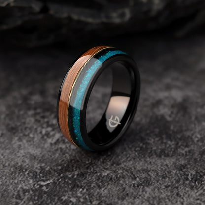 Black tungsten ring with brown whiskey barrel wood, gold-colored guitar string and blue opal inlays