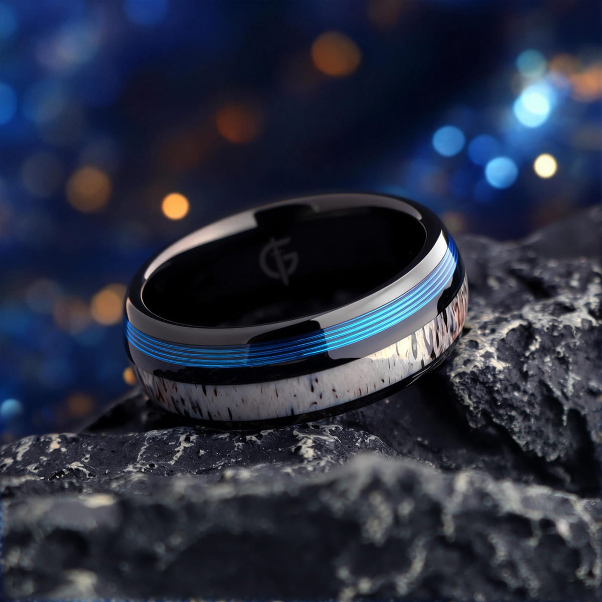 Domed black tungsten ring with blue fishing line and brown-patterned pale deer antler in separate grooves