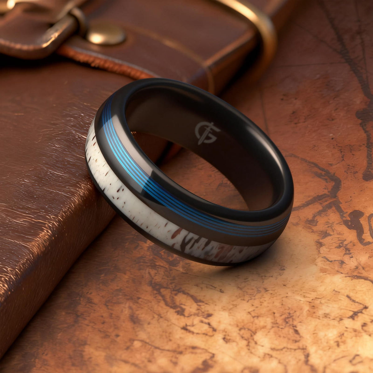 Domed black tungsten ring with blue fishing line and brown-patterned pale deer antler in separate grooves