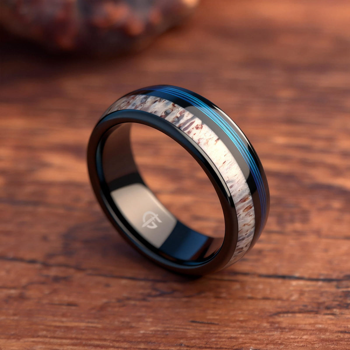 Domed black tungsten ring with blue fishing line and brown-patterned pale deer antler in separate grooves
